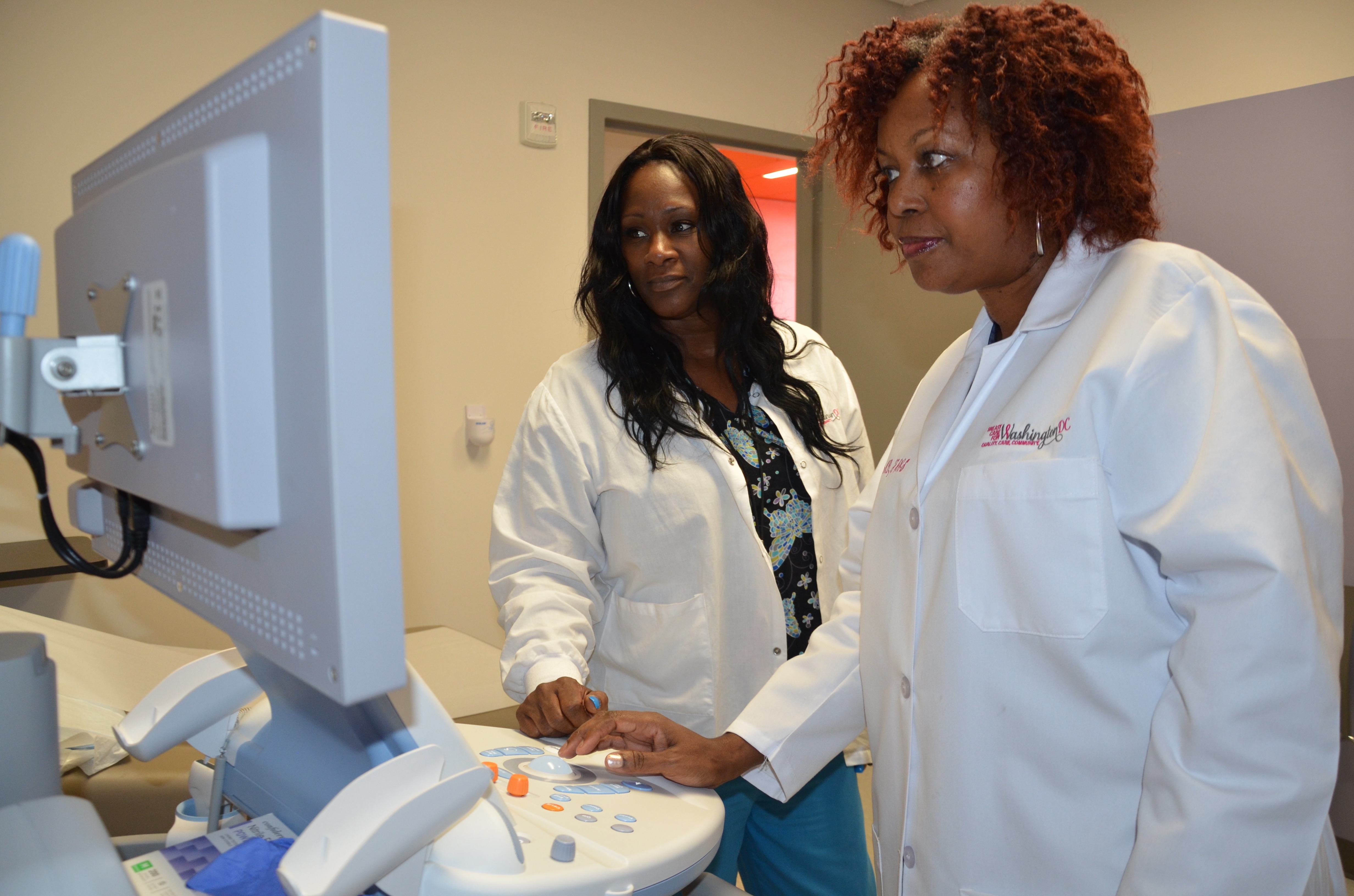 Two black female medical providers reading a screen on a medical device